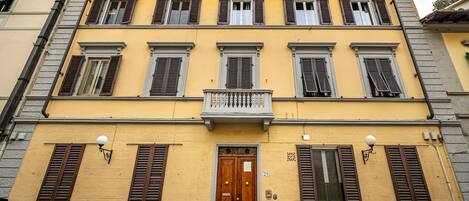 A yellow building with multiple windows and a wooden door.