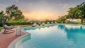 A swimming pool with lounge chairs and a hanging chair, surrounded by greenery and a sunset view. - Villa San Miniato in San Miniato (San Miniato)