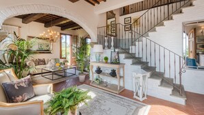 Un salon spacieux avec un escalier, une table basse, des canapés et divers objets de décoration.