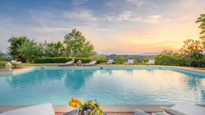 A swimming pool with lounge chairs and a decorative arrangement of lemons and flowers. - Villa San Miniato in San Miniato (San Miniato)