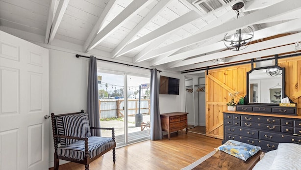 A spacious bedroom with a large bed, a wooden dresser, a chair, and a sliding glass door leading to a balcony. - 3 Bedroom/OnSuite X-Large His & Her Dual Showers bathroom, 5 min to Downtown, Free Large Gated Parking (San Antonio)