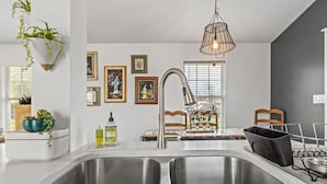 A modern kitchen with a double sink, hanging plants, framed pictures on the wall, and a pendant light. - 3 Bedroom/OnSuite X-Large His & Her Dual Showers bathroom, 5 min to Downtown, Free Large Gated Parking (San Antonio)