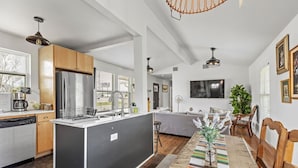 A modern kitchen with a central island, a dining area with a colorful rug, and a living space with a sofa and a TV. - 3 Bedroom/OnSuite X-Large His & Her Dual Showers bathroom, 5 min to Downtown, Free Large Gated Parking (San Antonio)