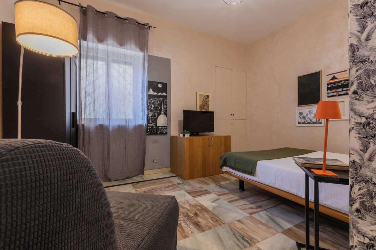 Une chambre à coucher avec un lit, une télévision, une lampe et une armoire.