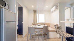 A compact room with a kitchenette, a dining area with a table and chairs, a sofa, and a decorative chair.