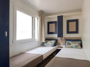 A compact room with two beds, a window, and a small table.