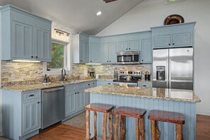 A kitchen with blue cabinets, granite countertops, a stainless steel refrigerator, and a built-in microwave. - Chalet with sweeping mountain views near Blowing Rock and Boone (Blowing Rock)