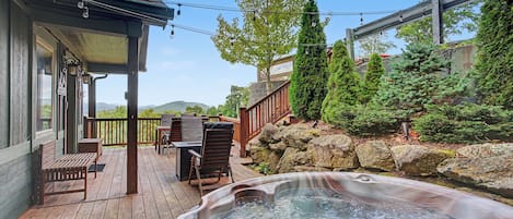 A wooden deck with outdoor furniture, a hot tub, and a stone wall.