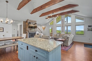 A spacious kitchen with a granite island, wooden beams, and large windows offering a view of the outdoors. - Chalet with sweeping mountain views near Blowing Rock and Boone (Blowing Rock)