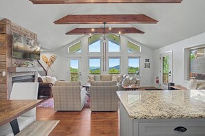 A spacious living area with a large window, wooden beams, and a fireplace. - Chalet with sweeping mountain views near Blowing Rock and Boone (Blowing Rock)