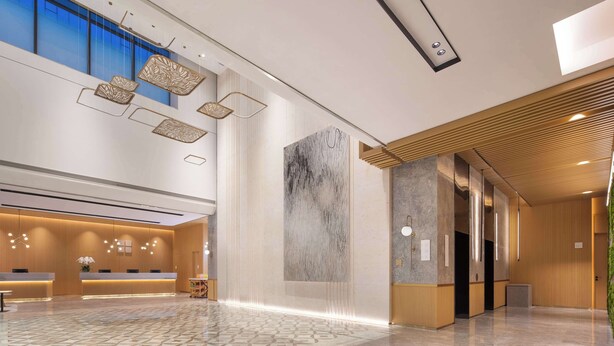 Un hall d’entrée spacieux avec un comptoir de réception, une grande œuvre d’art abstraite murale et un plafond haut orné de luminaires suspendus.