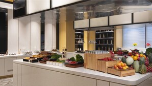 Une cuisine moderne dotée d’un îlot central où sont disposés des fruits, des légumes et divers condiments.