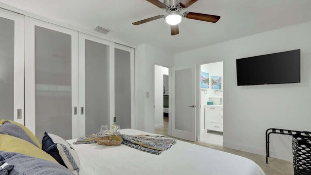A bedroom with a bed, a ceiling fan, a television, and a wardrobe. - Relaxing Retreat 2BR Oasis w/ Pool and Outdoor BBQ (Pembroke Pines)