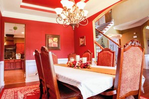 Classic dining room with a traditional setup, featuring a dining table for four, a chandelier, and a floral centerpiece.