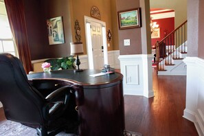 Work in comfort with a desk and leather chair in this traditional office space featuring a staircase and a framed painting.