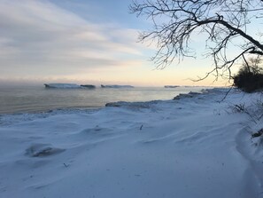 Eine verschneite Landschaft mit einem zugefrorenen See und Eisbergen in der Ferne.
