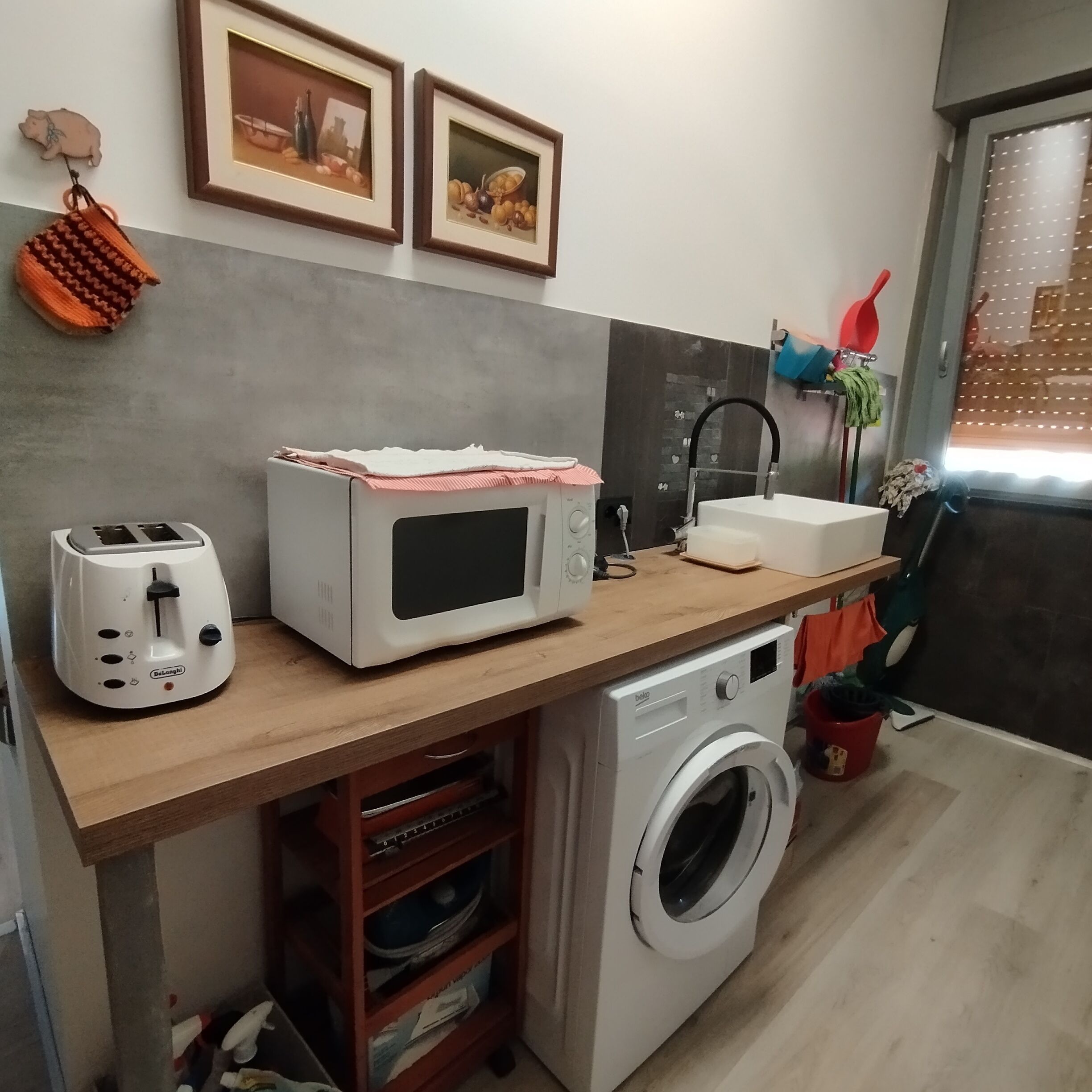 A compact kitchen with a microwave, toaster, sink, and washing machine.