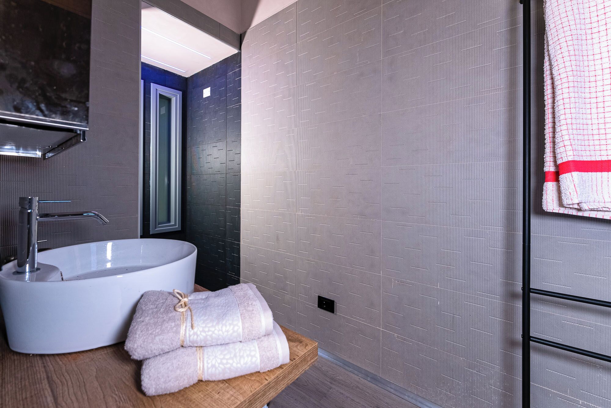Ein modernes Badezimmer mit einem weißen Waschbecken, einem Spiegel und einem Handtuchhalter.