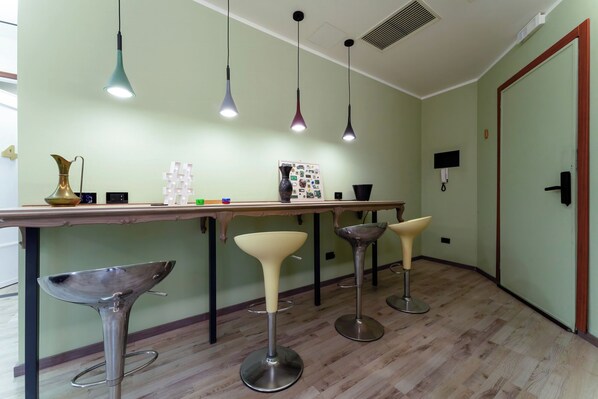 A modern kitchen with a wooden countertop, bar stools, pendant lights, and a decorative vase.