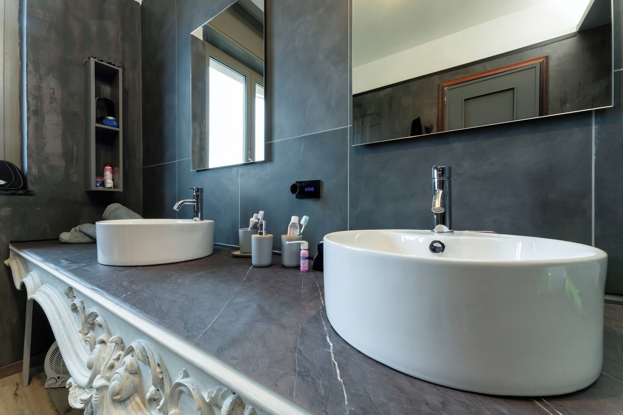 Un baño moderno con dos lavamanos blancos grandes, un espejo y un estante empotrado.