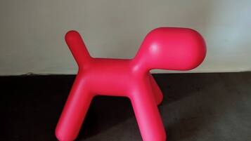 A red plastic dog-shaped object on a dark floor against a plain wall.
