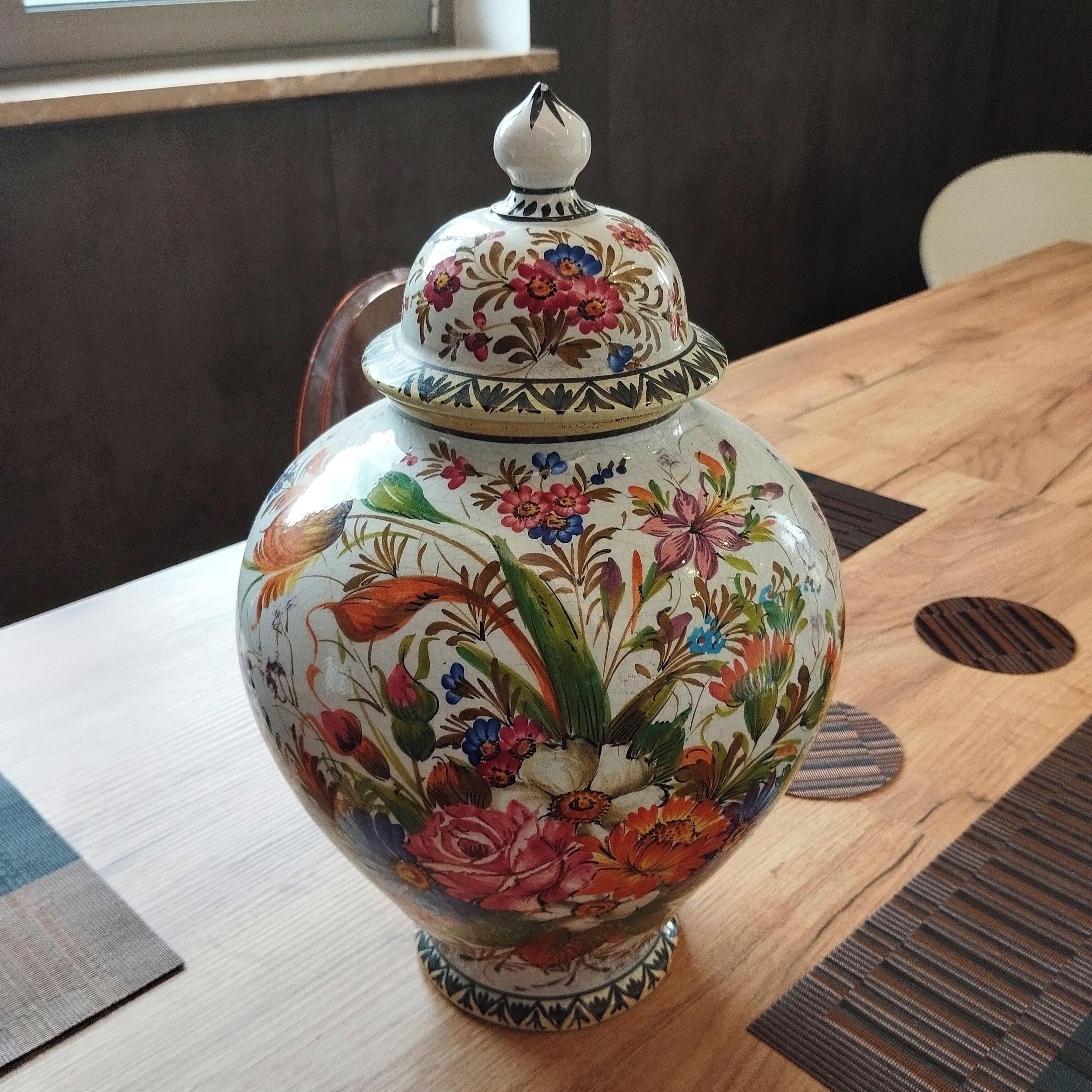 Un vase en céramique orné de motifs floraux, posé sur une table en bois.