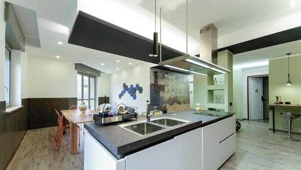Una cocina moderna con una isla central, electrodomésticos integrados y un comedor con mesa y sillas de madera.
