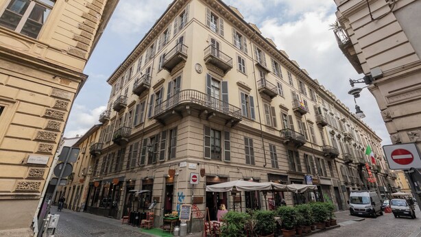 Un edificio histórico con varios balcones, terraza al aire libre y una calle adoquinada.
