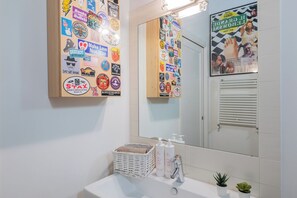 A bathroom with a sink, mirror, and various stickers on the walls. - La Corte by Wonderful Italy (Turin)
