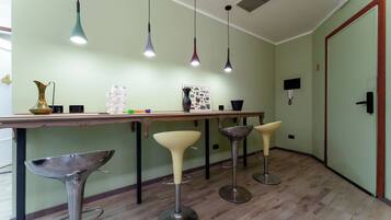 A modern kitchen with a wooden countertop, bar stools, pendant lights, and a decorative vase.