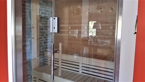 A sauna with a glass door, wooden interior, and a control panel.