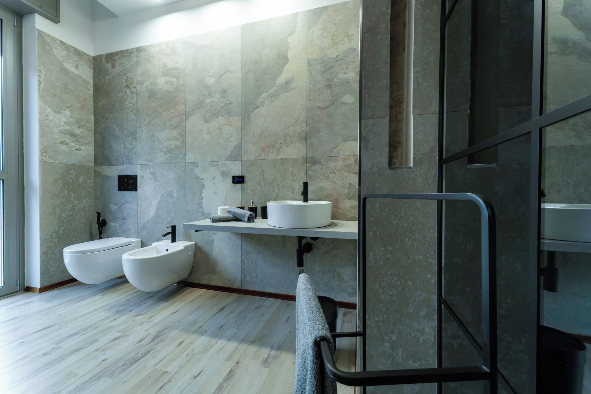 Un baño moderno con un espejo grande, un lavamanos blanco, un inodoro y un bidé.