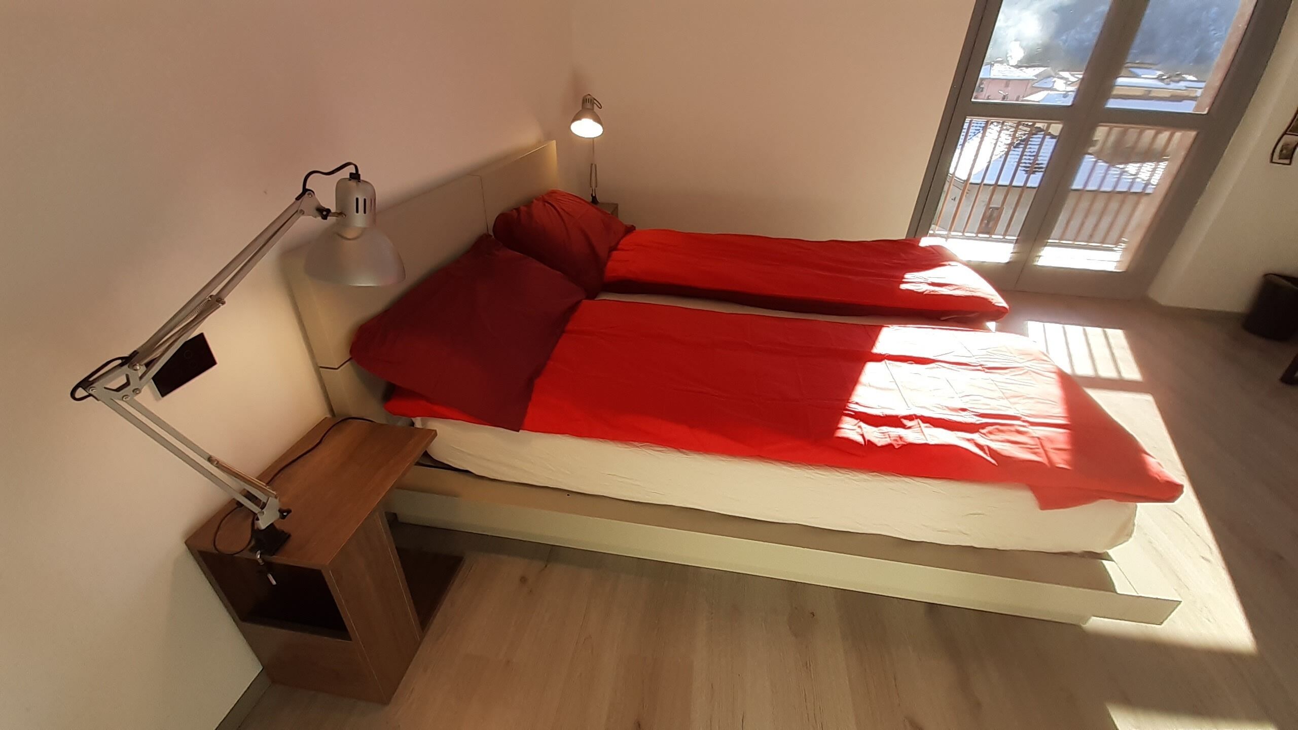Et værelse med seng, skrivebord og et vindue.