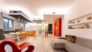 A modern living room with a grey sofa, a red chair, and a dining area with a table and chairs. - Camere CA + Millo - Camera 3 (Crevacuore)