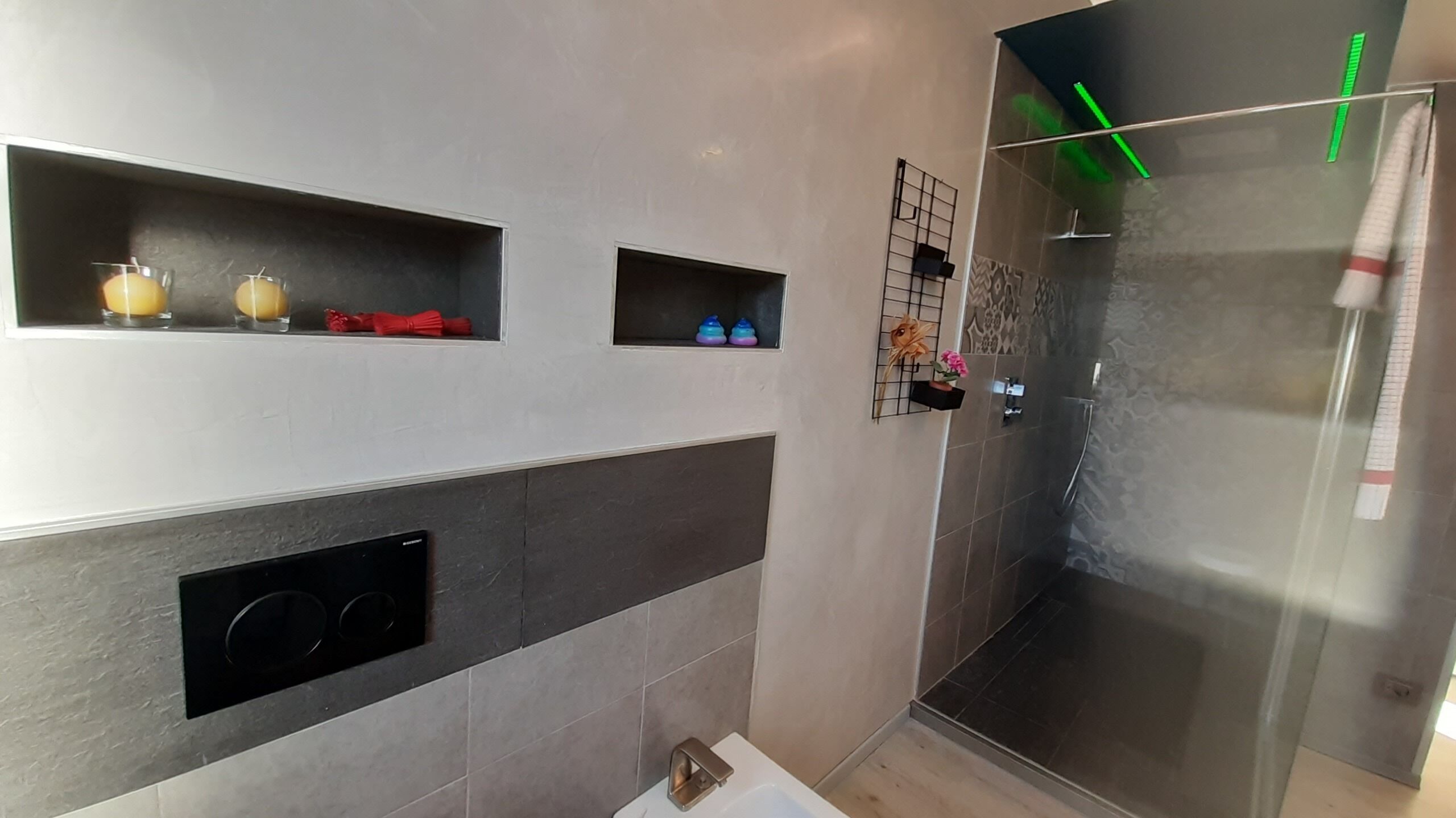 A modern bathroom with a glass shower enclosure, a built-in sink, and decorative shelves.