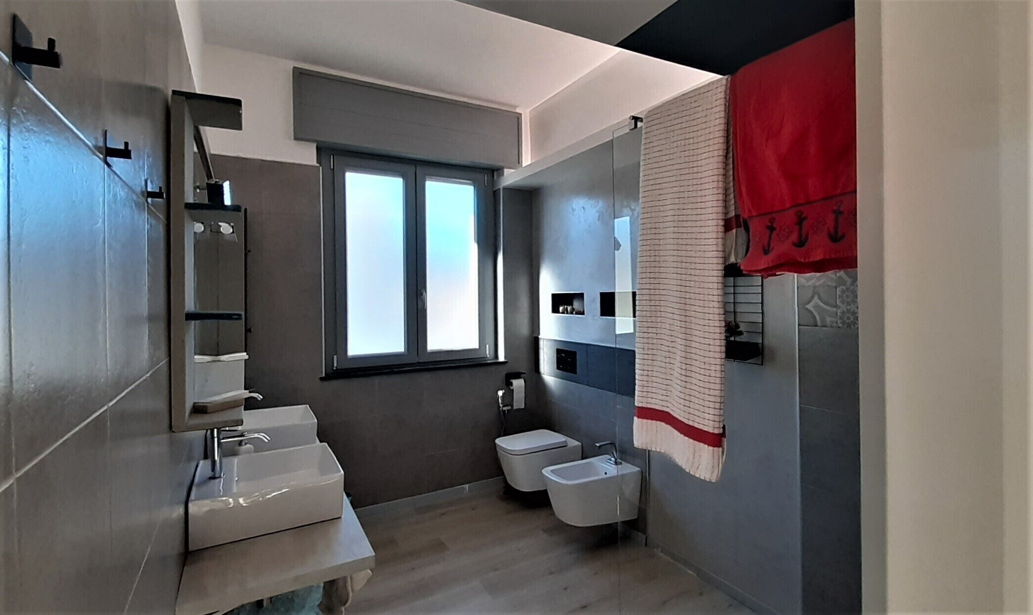 Uma casa de banho moderna com um espelho grande, duas pias, uma sanita e zona de duche.