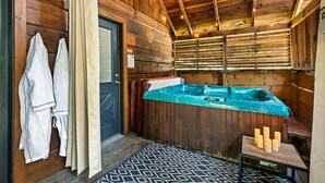 Una cabaña de madera con jacuzzi, toallas y velas.