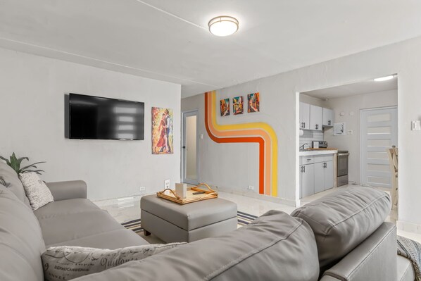 A modern living room with a grey sofa, a flat-screen TV, and artwork on the wall.