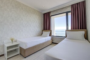 A hotel room with two beds, a nightstand, and a large window with curtains. - Apart hotel Novel (Korumdu)