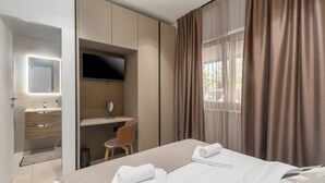 Een moderne hotelkamer met een bed, bureau, televisie en badkamer.