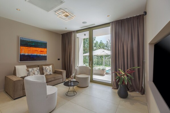 A modern living room with a sofa, armchairs, a coffee table, and a TV.