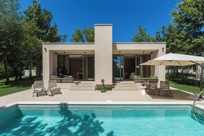 A modern house with a swimming pool, outdoor seating, and a patio area.
