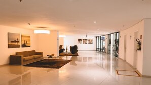 A spacious, modern hotel lobby with a polished floor, a sofa, a coffee table, and artwork on the walls. - Landscape Torre Platinum (Fortaleza)