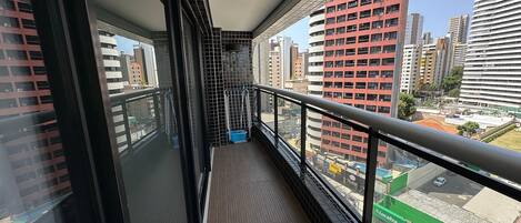 A balcony with a view of a cityscape, featuring tall buildings and a green area with a sign that reads "Localiza".