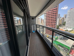 Un balcon offrant une vue sur le paysage urbain, avec de grands immeubles et un espace vert sur lequel on peut lire l’inscription « Localiza ».