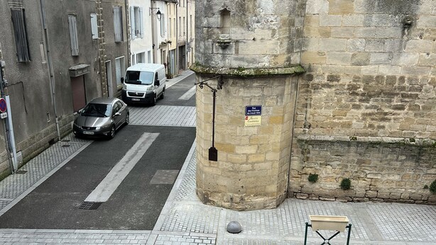 A narrow street with historic stone buildings, a parked car, and a bench. - Apartment historic center Monségur (Monségur)