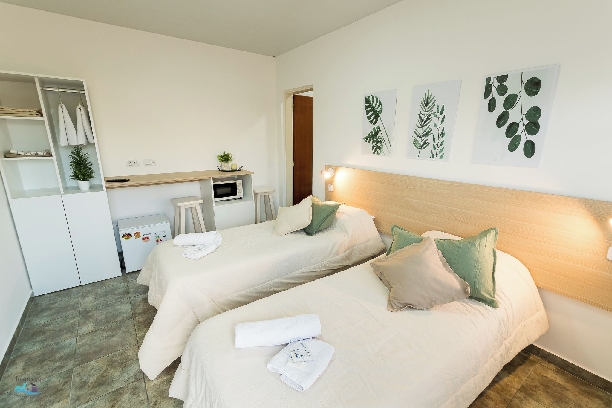 A hotel room with two beds, a desk, a microwave, and a wardrobe.