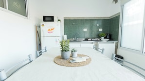 Een moderne keuken met een witte tafel, twee planten in potten, een magnetron en een spoelbak.