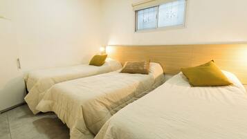 A room with two beds, each with a pillow and a bedside lamp.