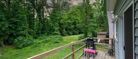 A deck with a wooden railing, a barbecue grill, and outdoor furniture.